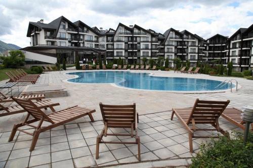 a resort with a pool and chairs and a building at Aspen studio Mountain retreat at Aspen Resort Golf Ski & Spa in Razlog