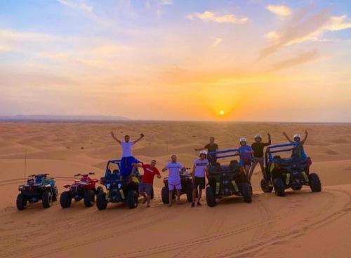 a group of people standing in the desert with atvs at Merzouga Luxurious Camp in Merzouga