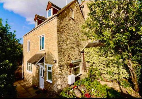 un grande edificio in mattoni con un albero di fronte di Quaint Cotswold Cottage a Chipping Norton