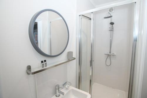 ein Bad mit einer Dusche, einem Waschbecken und einem Spiegel in der Unterkunft Pass the Keys Lincoln room at Tavmar Apartments in Lincoln
