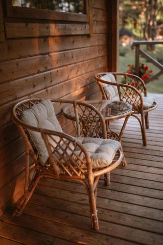three wicker chairs and a table on a porch at Miško kraštas in Vileikiai