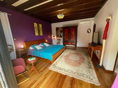 a bedroom with a blue bed and a purple wall at Villa Hermès chambre en suite parentale in Saint-Pierre