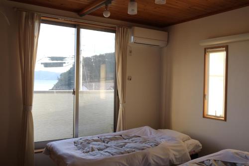 a bedroom with a bed and a large window at Vacation House YOKOMBO ANNEX in Naoshima