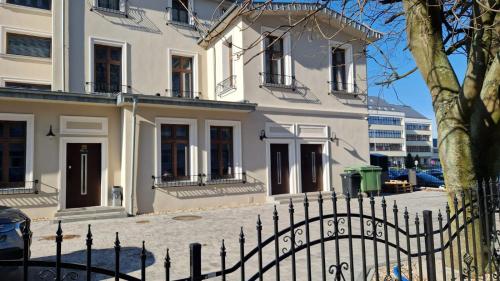 a white house with a fence in front of it at APARTAMENT JARACZA 28/10 in Słupsk