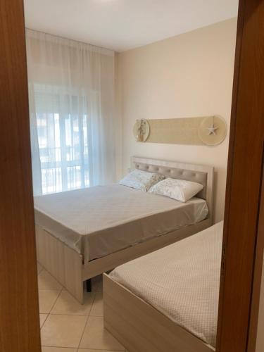 a bedroom with two beds and a window at Melody Apartament 1 in Golem