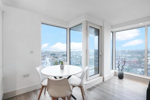 a dining room with a table and chairs and large windows at Luxury Apartment With Stunning Views on 10th floor in Edgware