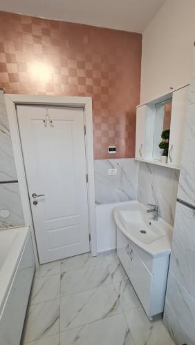 La salle de bains blanche est pourvue d'une porte blanche et d'un lavabo. dans l'établissement Jafar Resort 2, à Timişoara