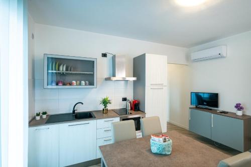 a kitchen with white cabinets and a table and a tv at Milena Suite Apartments in Alghero