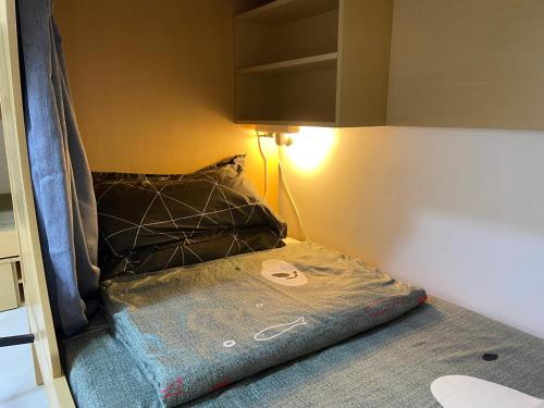 a bed in a small room with a pillow and a lamp at Loong Hostel in Riyadh