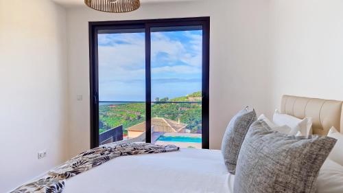 a bedroom with a bed and a large window at Allure Alannas Villa by LovelyStay in Funchal