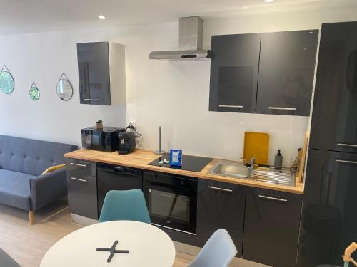 une cuisine avec des armoires noires, une table et des chaises dans l'établissement T2 fonctionnel & confortable en RdC sur cour calme, à Saint-Florentin