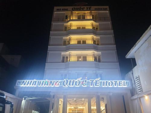 um edifício alto e branco com um cartaz à noite em khách sạn Quốc Tế em Cà Mau
