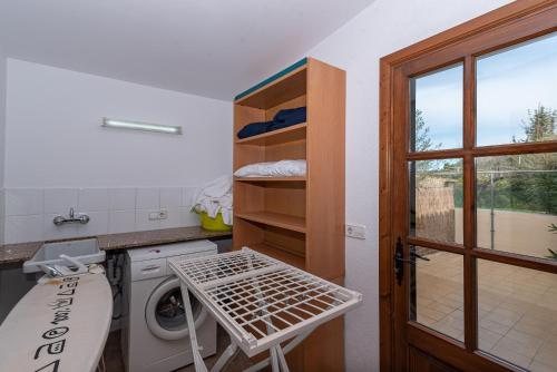 eine Waschküche mit einer Waschmaschine und einem Fenster in der Unterkunft Villa Cuxach Mateu in Pollença