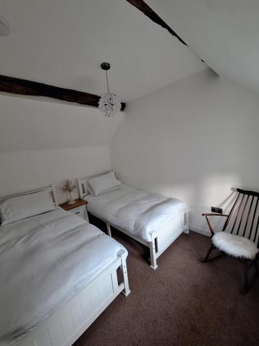 a bedroom with two white beds and a chair at Mount Cottage in Shrewsbury