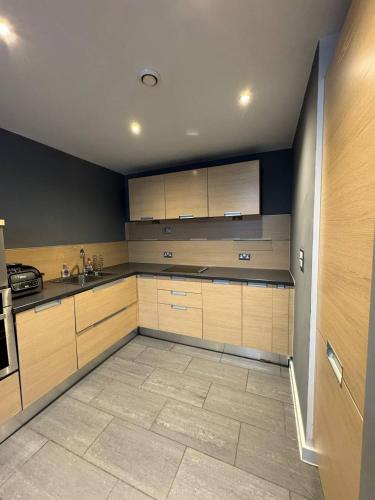 a kitchen with wooden cabinets and a tile floor at City Centre 1 bedroom apartment in Manchester