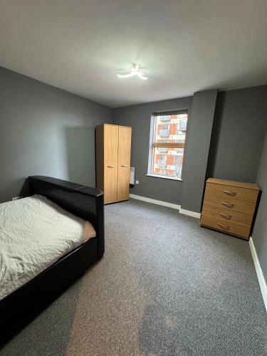 a bedroom with a bed and a dresser and a window at City Centre 1 bedroom apartment in Manchester