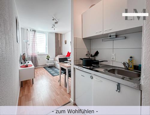 マインツにあるLM-ApartmentsMainz-03の白いキャビネットとシンクとテーブルのあるキッチン