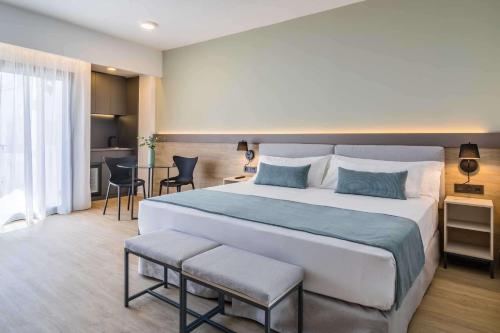 マルベーリャにあるOccidental Puerto Banúsの大きなベッドとテーブルが備わるホテルルームです。