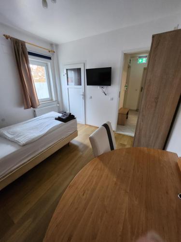 a bedroom with a bed and a table and a television at Pension Seevetal in Seevetal