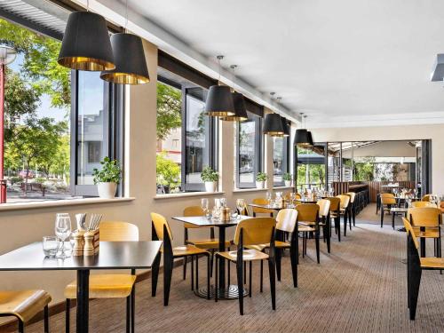柏斯的住宿－Mantra on Hay Perth，餐厅设有桌椅和窗户。