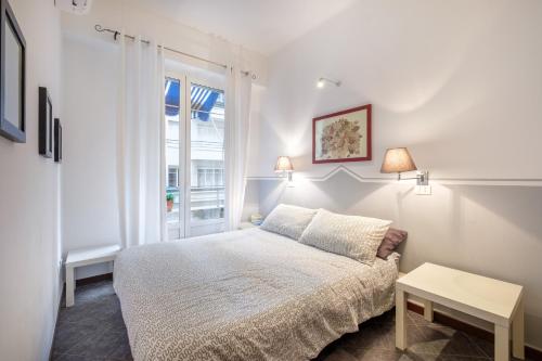 a white bedroom with a bed and a window at Florence in Nice