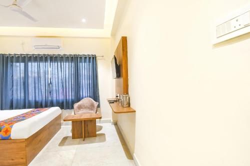 a bedroom with a bed and a chair and a window at FabHotel Prime The Golden Plaza - Nr Tarapith Temple in Tarapith