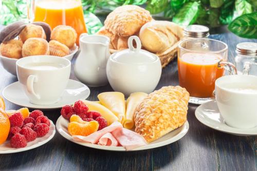 a table with plates of breakfast foods and drinks at Hotel Neumarkt in Berg bei Neumarkt