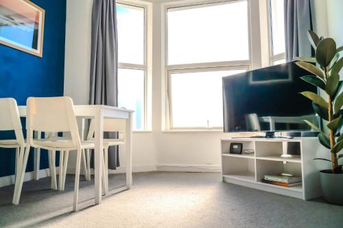 a living room with a table and chairs and a tv at Spacious 2BD Maisonette with Lush Loft in Newquay in Newquay