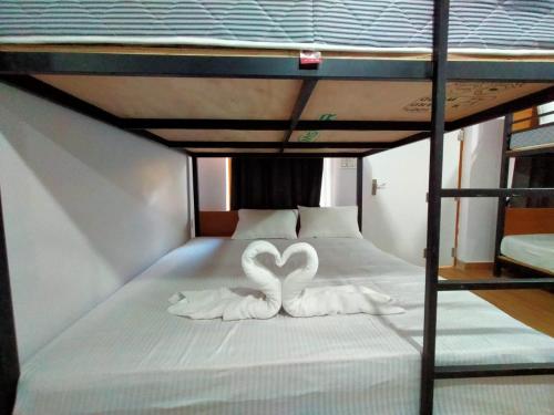 two swans shaped like hearts are sitting on a bed at West Coast Gokarna in Gokarna