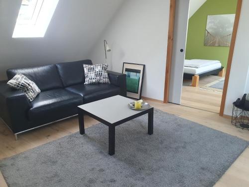 Sala de estar con sofá de cuero negro y mesa de centro en ZwischenRaum en Wuppertal