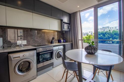 a kitchen with a white table and a table and chairs at The Capital On The Park Luxury Stay in Johannesburg