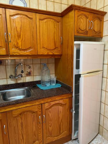 a kitchen with wooden cabinets and a sink and a refrigerator at Casa Pepa in Puerto de Mogán