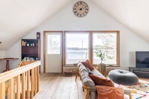 a living room with a couch and a clock on the wall at Beautiful Expansive House with Sea views, large private bedrooms available in shared house in Vaasa