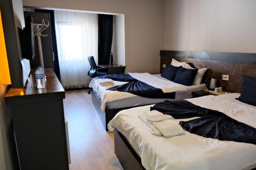 a hotel room with three beds and a desk at Atlas Otel in Erzurum