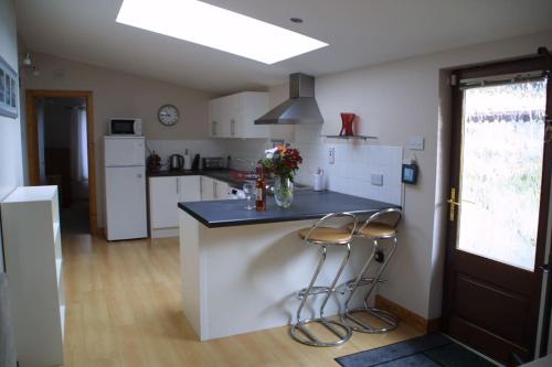 cocina con encimera y 2 taburetes en Bright spacious mews in great location, en Booterstown