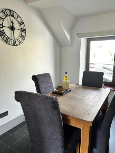 a dining room table with chairs and a clock on the wall at Cadwgan House in Rhayader