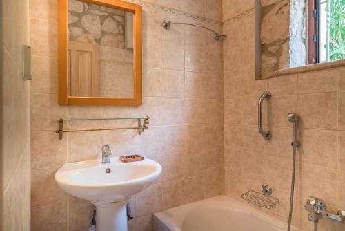 y baño con lavabo, espejo y bañera. en Myrties stone houses - Ta Petrina en Vasilikos