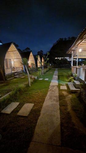 a person walking down a path in a yard at night at Batur cottage in Kubupenlokan