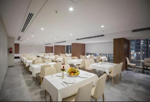 uma sala de jantar com mesas brancas e cadeiras brancas em فندق ماسة المشاعر الفندقية em Meca