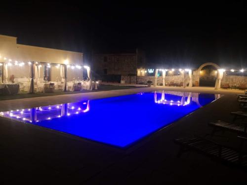 una piscina iluminada por la noche con luces en Agriturismo Masseria Quaremme, en Carpignano Salentino
