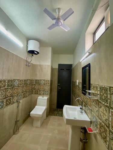 a bathroom with a toilet and a sink and a ceiling fan at hello Namaste India-Elite in Jaipur