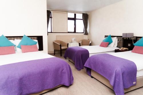 two beds in a room with purple blankets on them at Caladh Inn in Stornoway