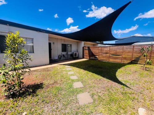 ein Haus mit einem Zaun und einem Garten mit einem Baum in der Unterkunft 'Your Place on Davidson' in Mount Isa