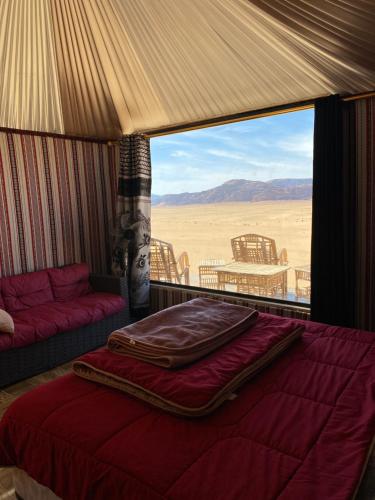 a bed in a tent with a view of the desert at Wadi Rum alsultan Camp in Wadi Rum