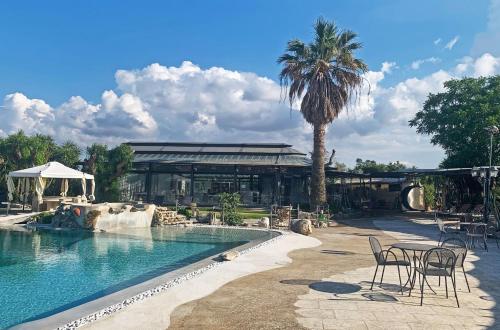 une piscine avec des chaises et un palmier ainsi qu'un bâtiment dans l'établissement Masseria Don Vito, à Merine