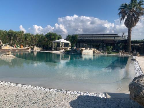 a large swimming pool with a fountain in a resort at Masseria Don Vito in Merine