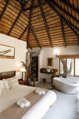a bedroom with a large bed and a bath tub at Duma Manzi Eco Lodge & Spa in Richmond