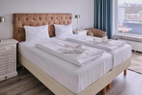 een slaapkamer met een groot wit bed met twee witte gerechten erop bij H24 Factory Apartments Wolfsburg in Wolfsburg