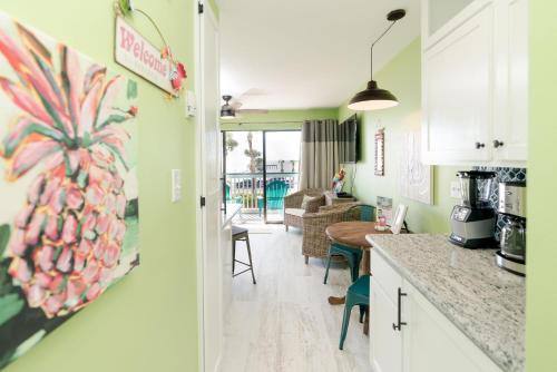 a kitchen and living room with a pineapple painting on the wall at Turtley Awesome Beachfront Condo Pool in Galveston