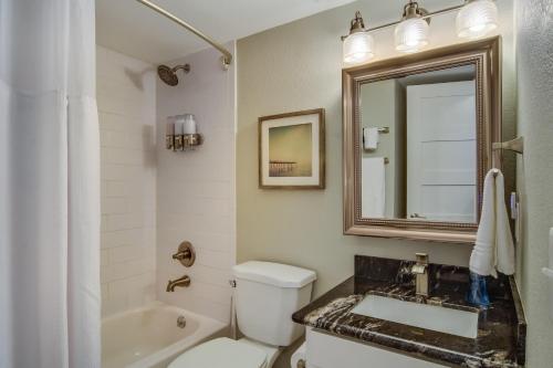a bathroom with a toilet and a sink and a mirror at CDM 201 - Pier Paradise in Galveston